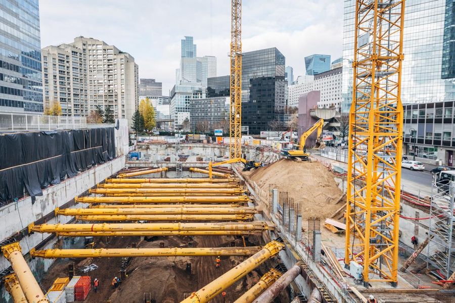 Vue aérienne d’un chantier de construction à La Défense, avec deux grandes grues jaunes et des tours de bureaux en arrière-plan.